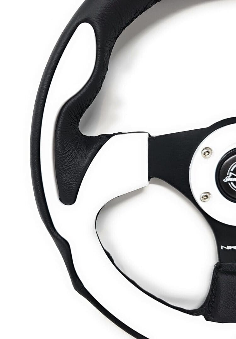 Close-up of a black and white steering wheel with a logo in the center.