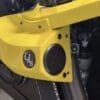 Close-up of a yellow machine part with a circular black component and small logo.