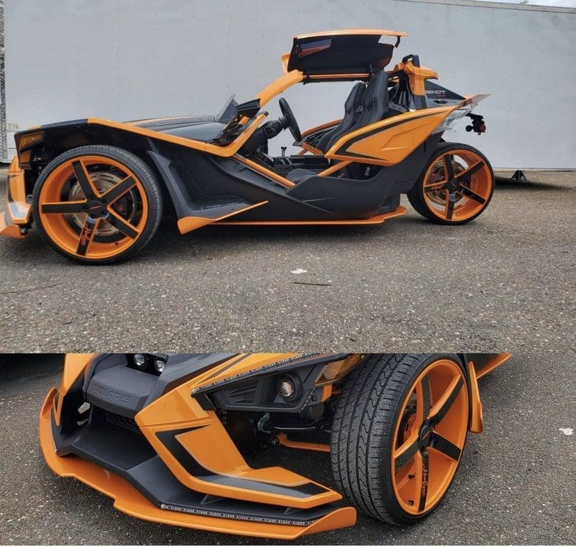 Sleek black and orange three-wheeled sports car with futuristic design.