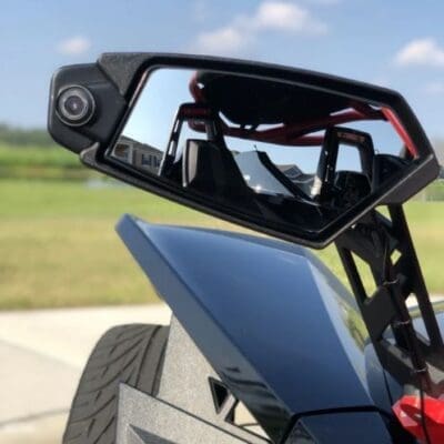 Close-up of a side mirror and part of a sleek vehicle with an open-air design.
