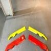 Four colorful plastic car spoiler parts on the floor.