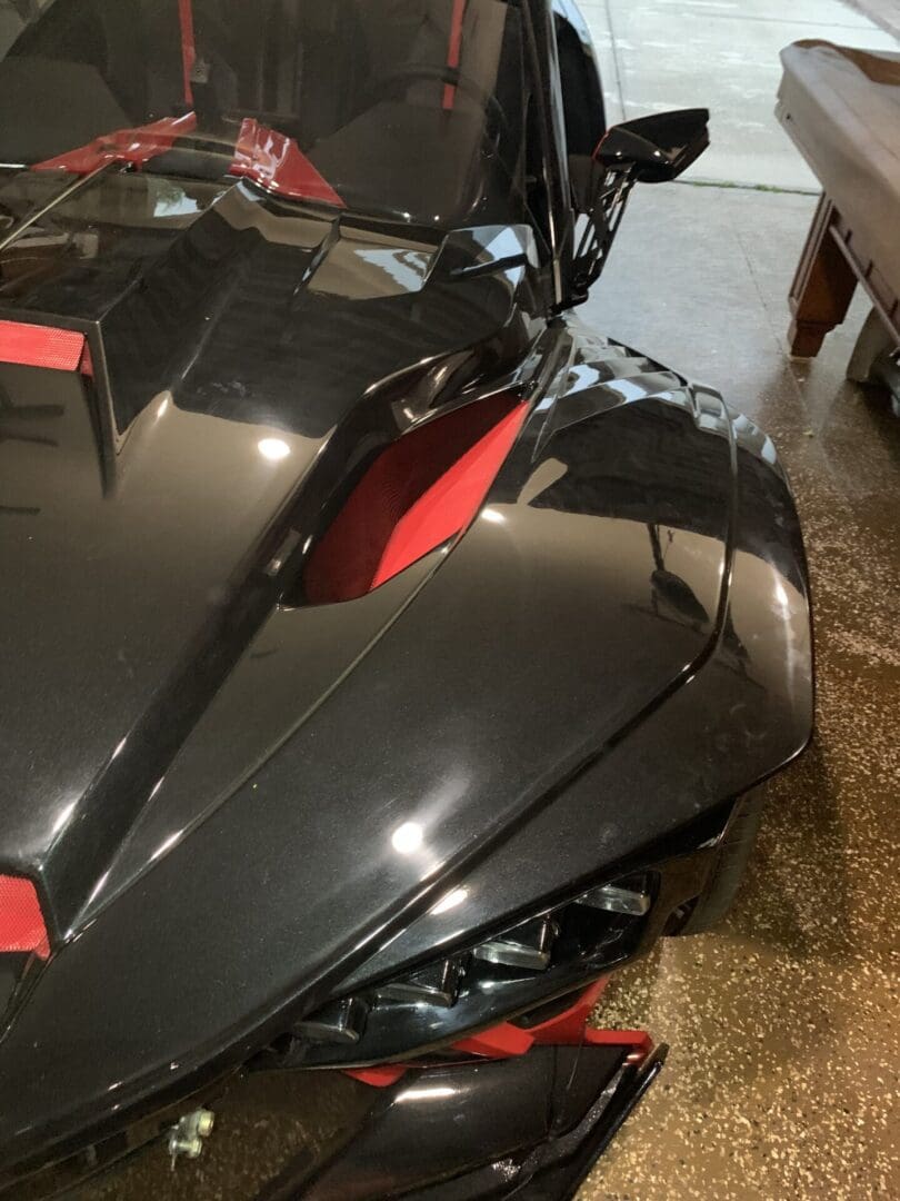 Close-up of a sleek black and red sports car hood with sharp angles.