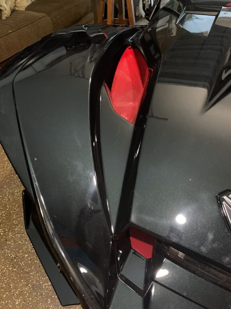 Close-up of a sleek black sports car's rear with red taillight and aerodynamic design.