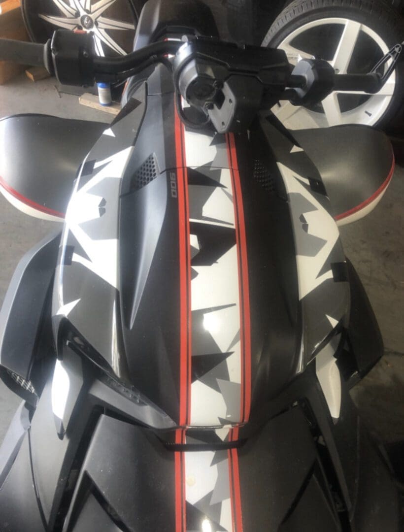 Close-up of a black vehicle with geometric white and red stripes.