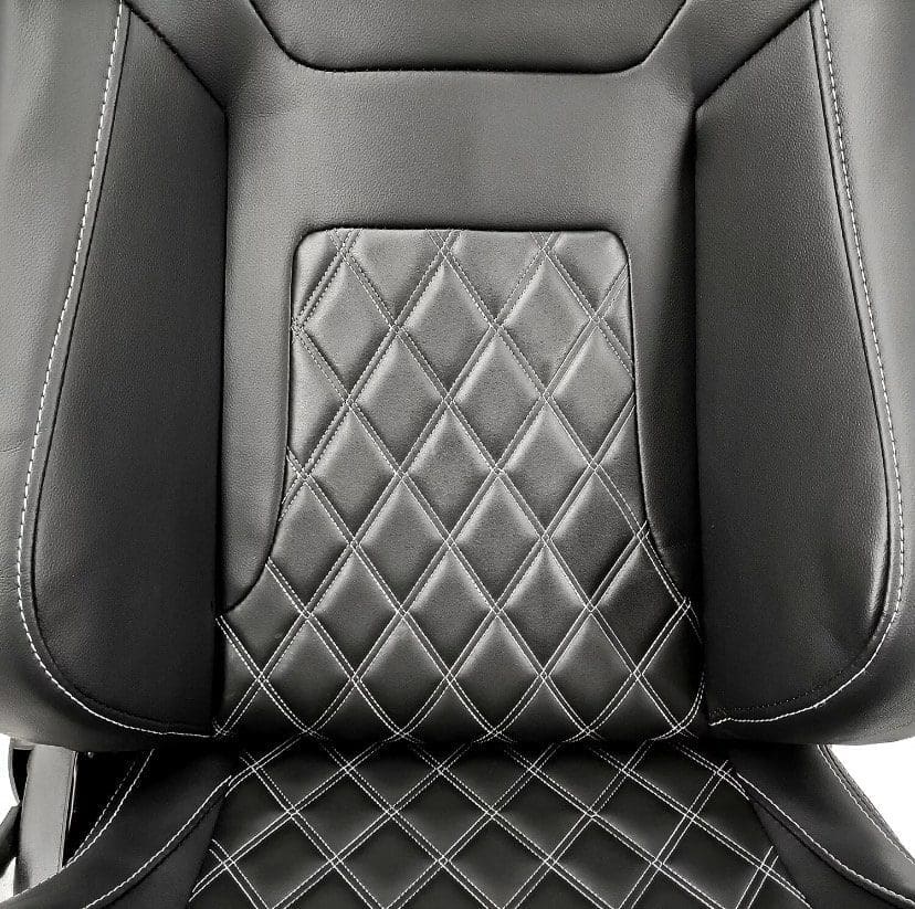 IMG_4969 Close-up of a black leather car seat with diamond-pattern stitching.
