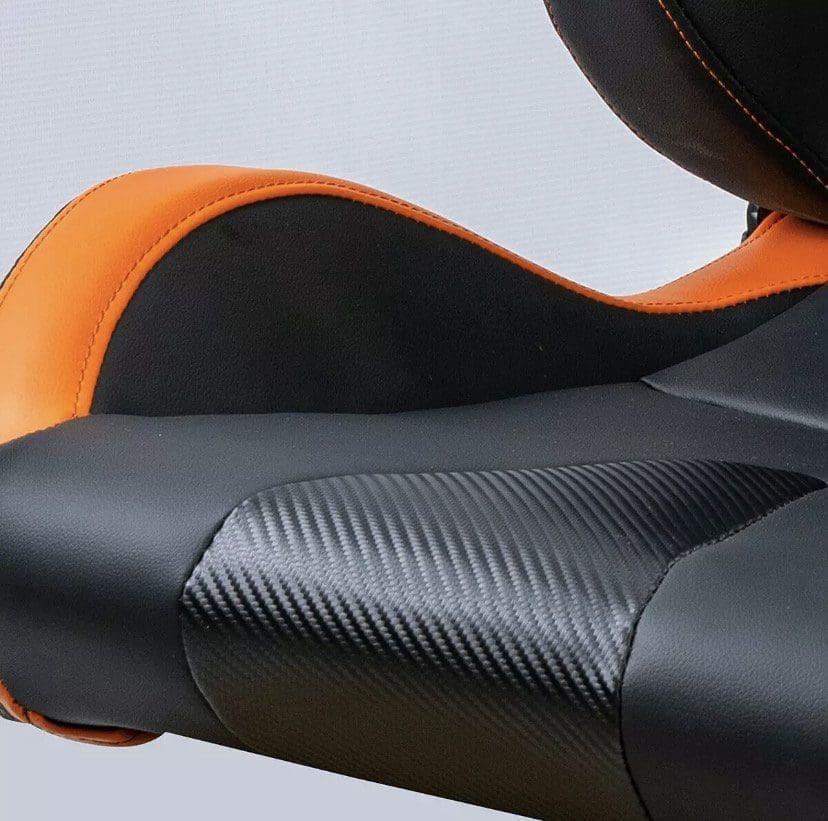 Close-up of a black and orange motorcycle seat with textured details.