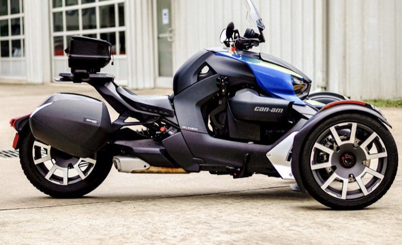 IMG_5314 A sleek Can-Am three-wheeled motorcycle parked on concrete outside a building.