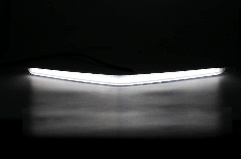 A V-shaped white LED light glowing in the dark.