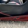 Close-up of a black car's lower side with red accents near the ground.