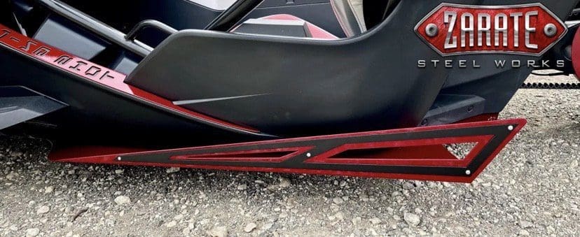 Close-up of a black car's lower side with red accents near the ground.