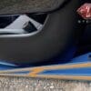 Close-up of a car door sill with blue and orange accents and a partial view of the interior.