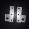 Two metal brackets with multiple holes on a black background.