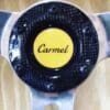 Close-up of a car steering wheel center with 'Carmel' logo.