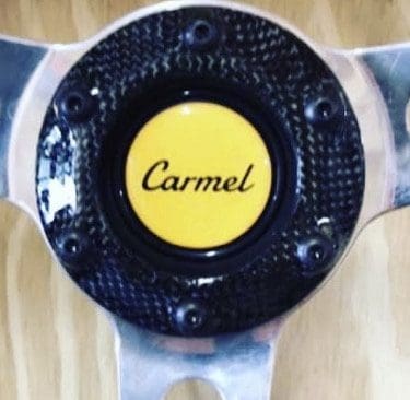 Close-up of a car steering wheel center with 'Carmel' logo.