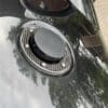 Close-up of a black car's fuel cap on a shiny surface.