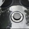 Close-up of a shiny black motorcycle fuel tank with a chrome fuel cap.