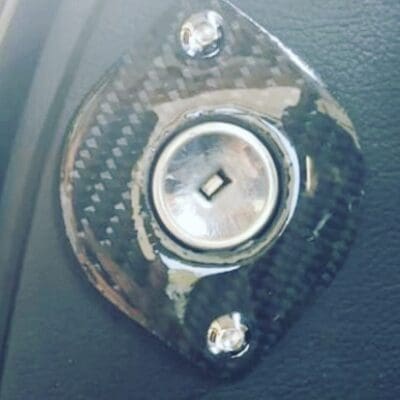 Close-up of a metallic rotary knob on a carbon fiber base.