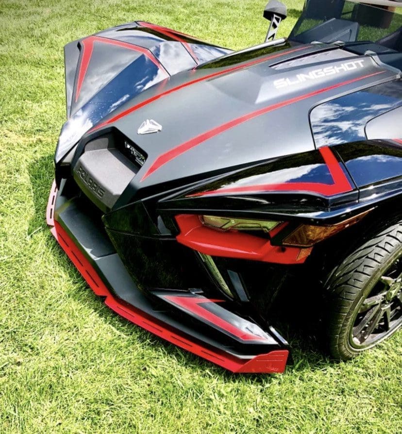 Close-up of a sleek black sports car with red accents on grass.