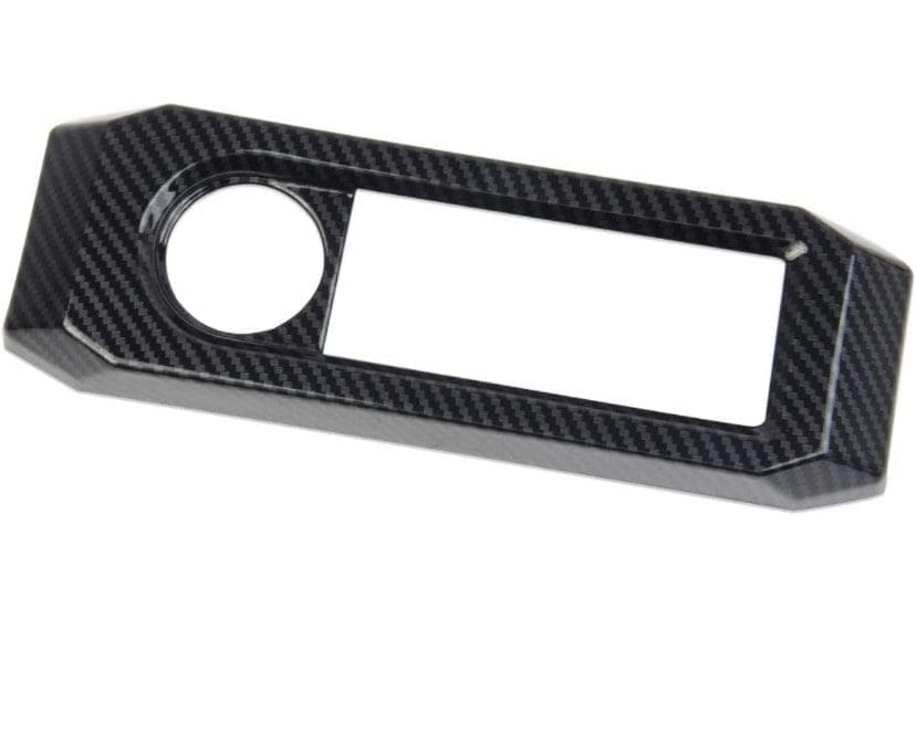 Carbon fiber car dashboard panel with circular and rectangular cutouts.