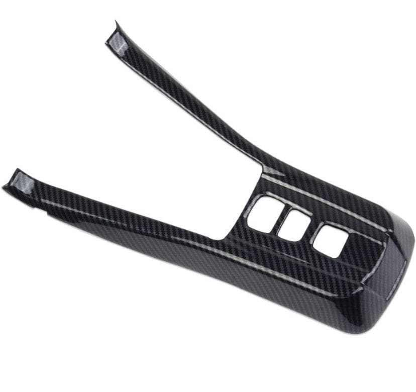 Black carbon fiber car center console cover with cutouts.