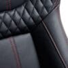 Close-up of black leather car seat with red stitching.