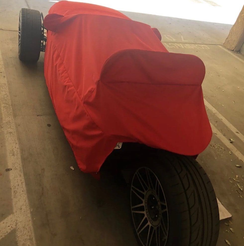A small vehicle covered with a red cloth, showing large wheels.