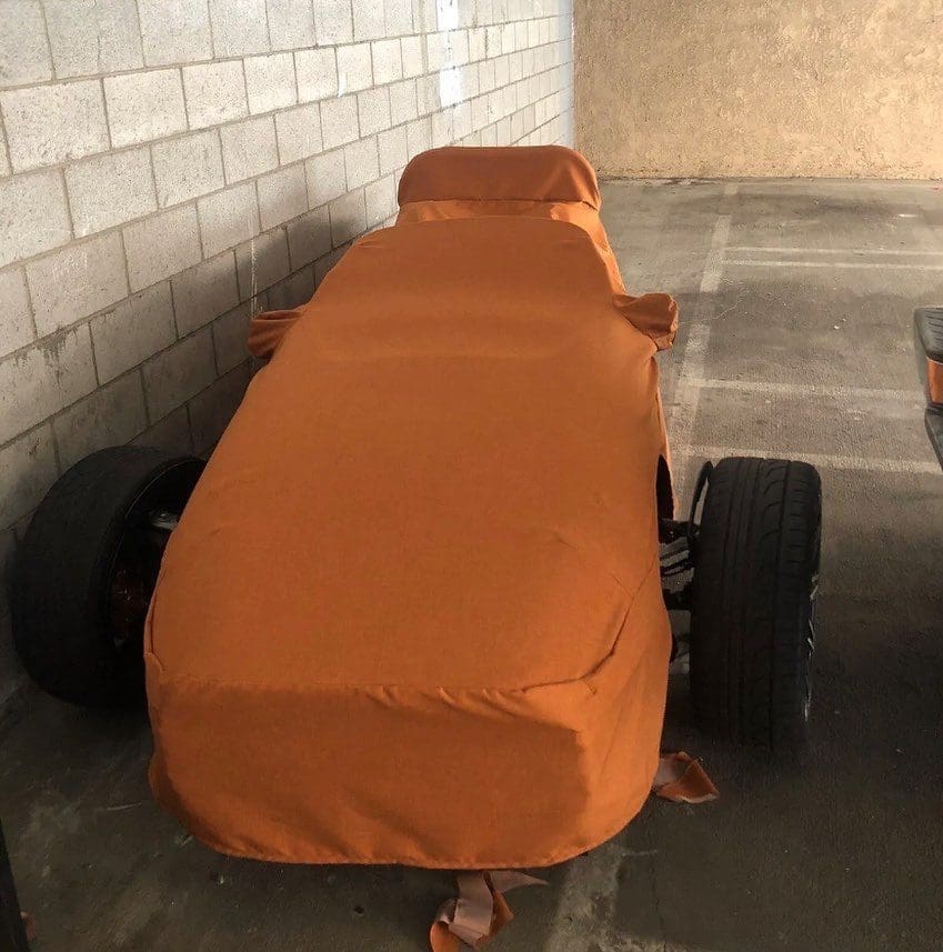 Cars covered in orange protective covers in a garage.