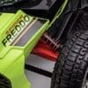 Close-up of a green off-road vehicle's suspension and tire.