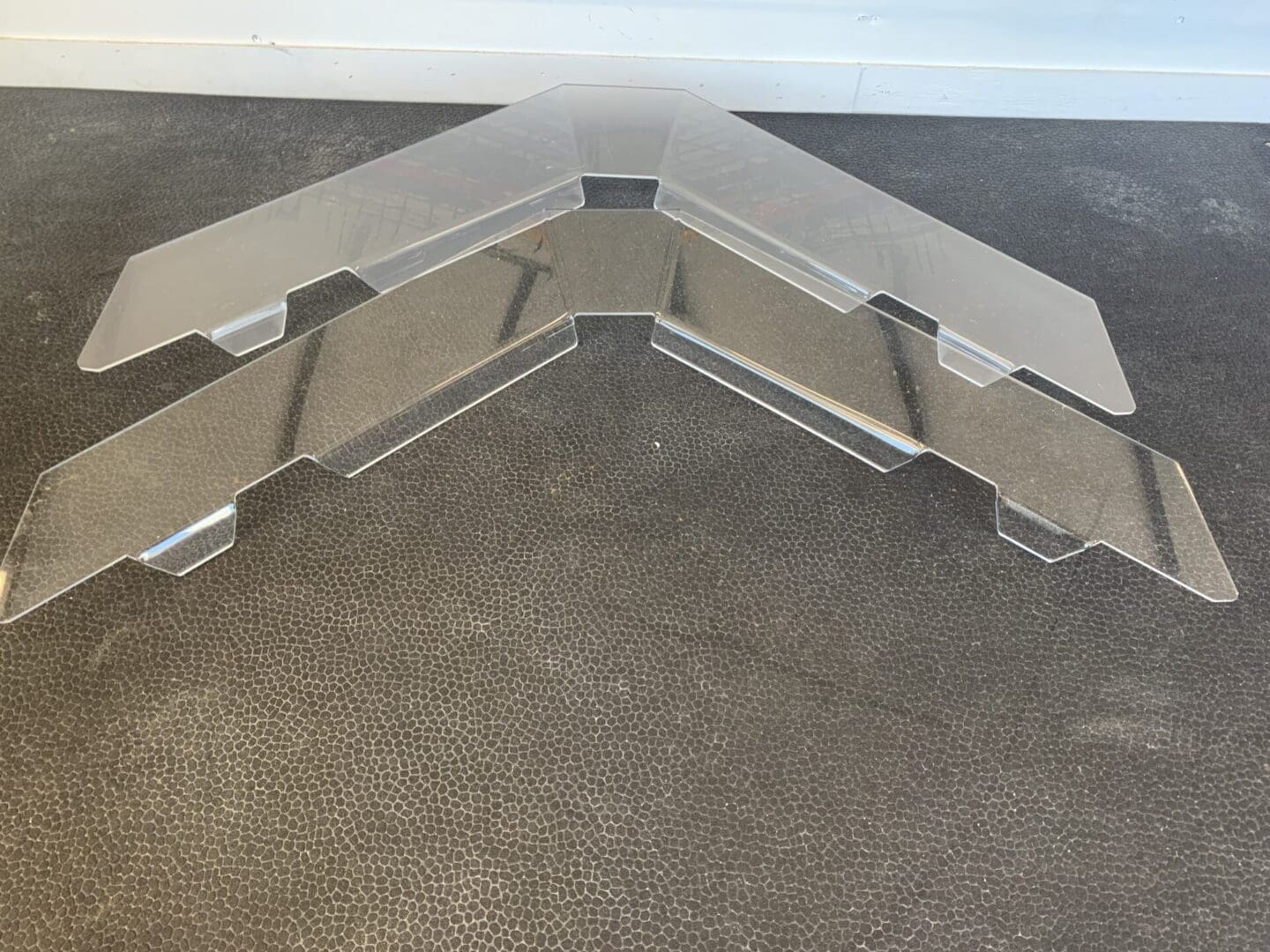 Two metal brackets joined at a corner on a dark surface.