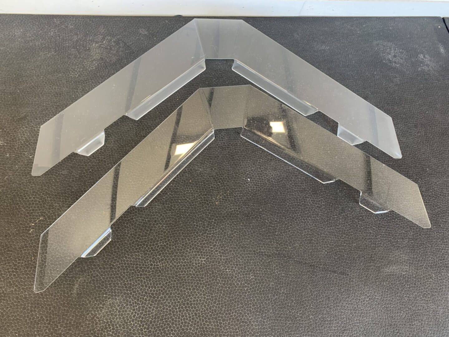 Metal bracket with multiple holes on a concrete surface.