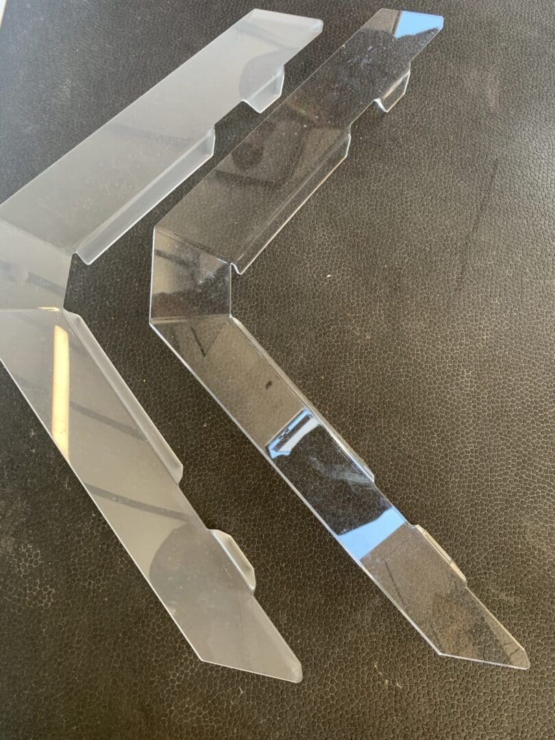 Two shiny metal hinges on a brown carpet surface.