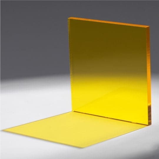 A transparent yellow acrylic sheet standing and lying flat on a gray surface.