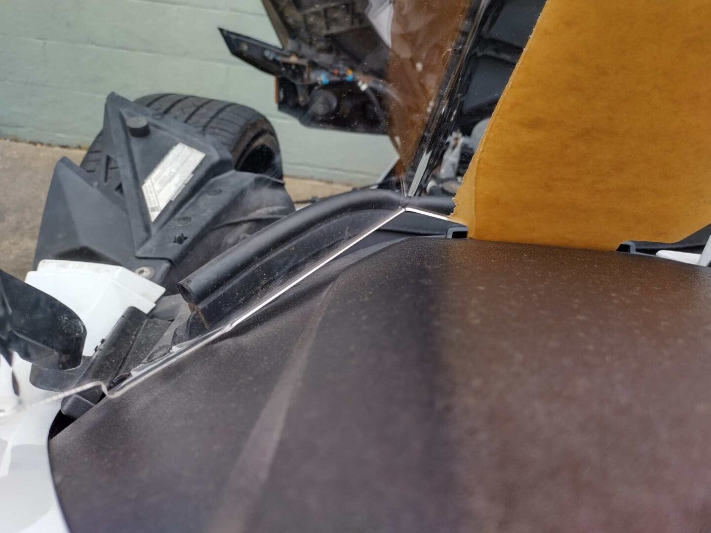 Close-up of a damaged car engine compartment with exposed wiring and broken parts.