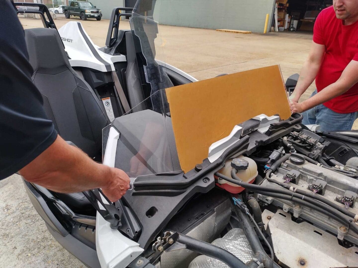 Two people working on a car engine with the hood open.