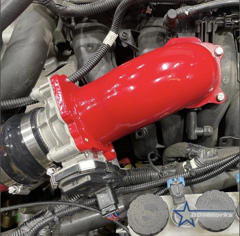 Bright red silicone intake hose installed in a car engine bay.