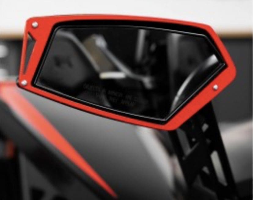 Close-up of a red side mirror on a vehicle showing part of the interior.