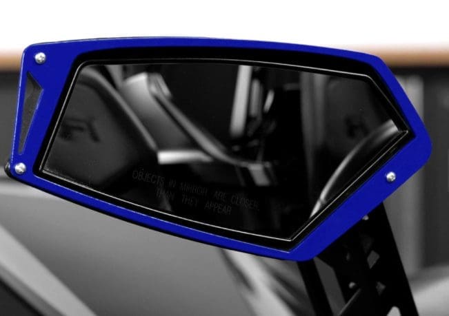 Close-up of a sleek blue car side mirror reflecting the interior.