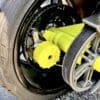 Close-up of a car wheel with a bright yellow lug nut cover and belt system.