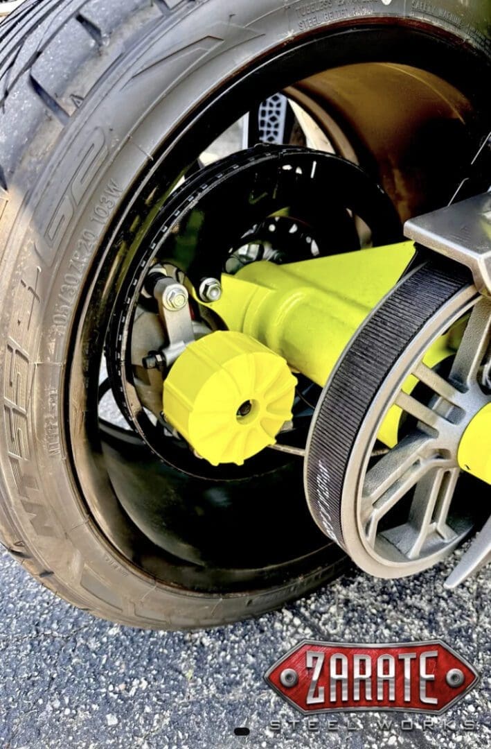 Close-up of a car wheel with a bright yellow lug nut cover and belt system.