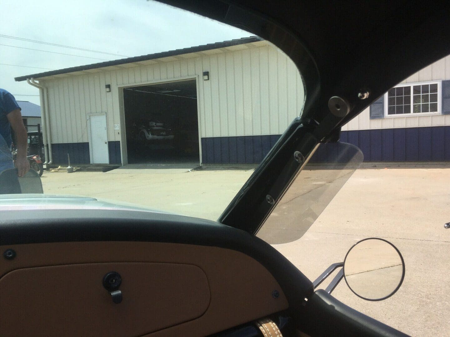 View from inside a vehicle looking out at a building with an open garage door.