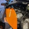 Close-up of an orange motorcycle fairing with visible engine parts.
