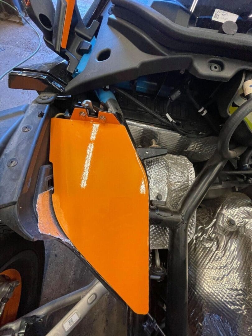 Close-up of an orange motorcycle fairing with visible engine parts.