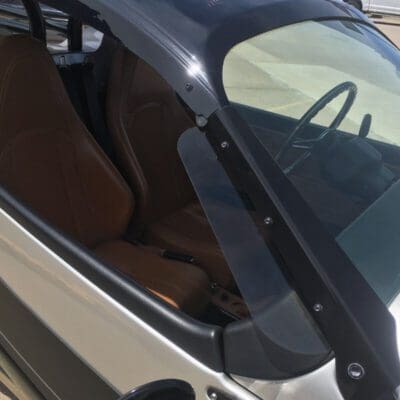 Close-up of a small car's interior showing the driver seat and windshield.