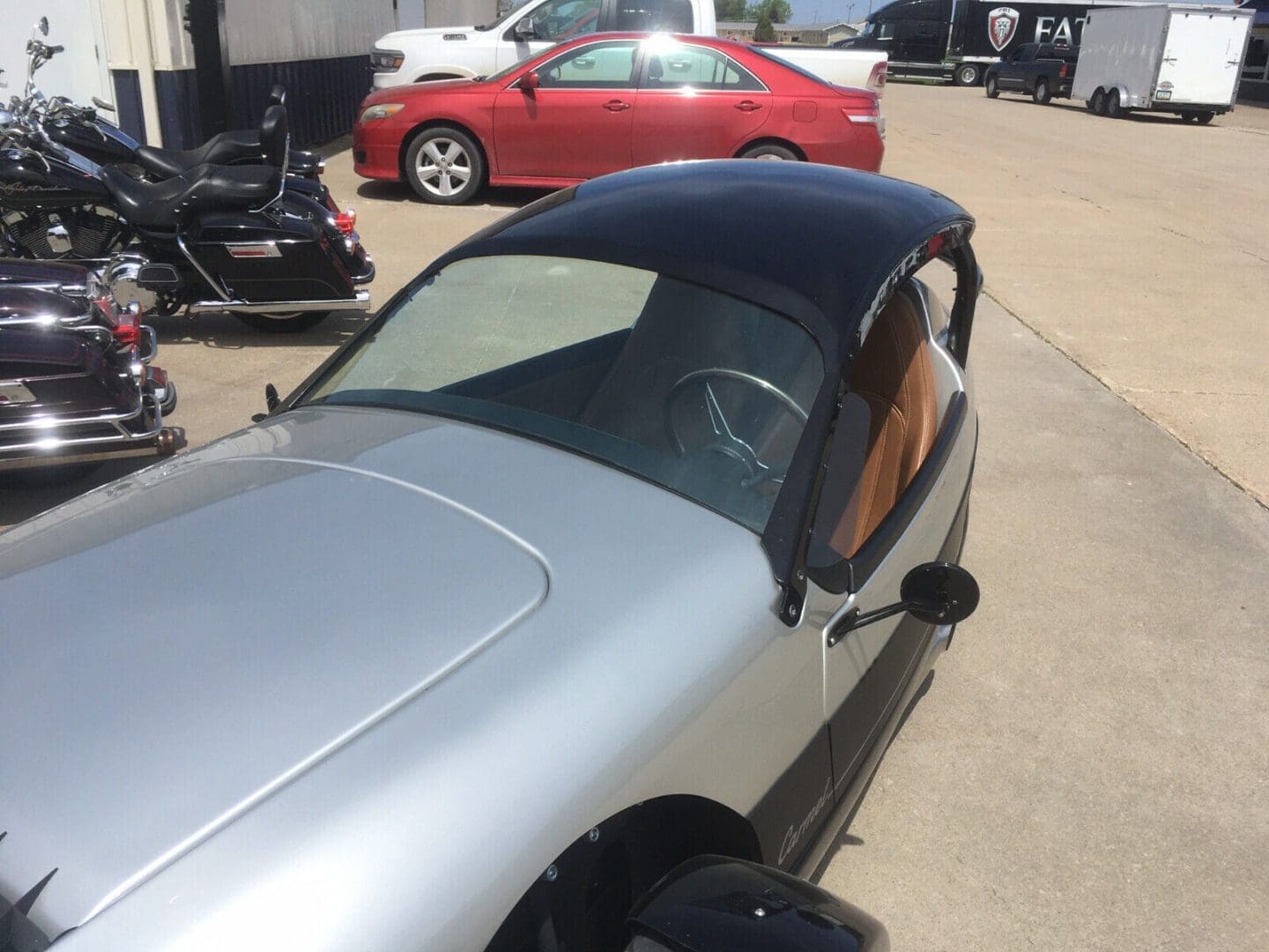 A silver convertible car with a black soft top roof parked outdoors.