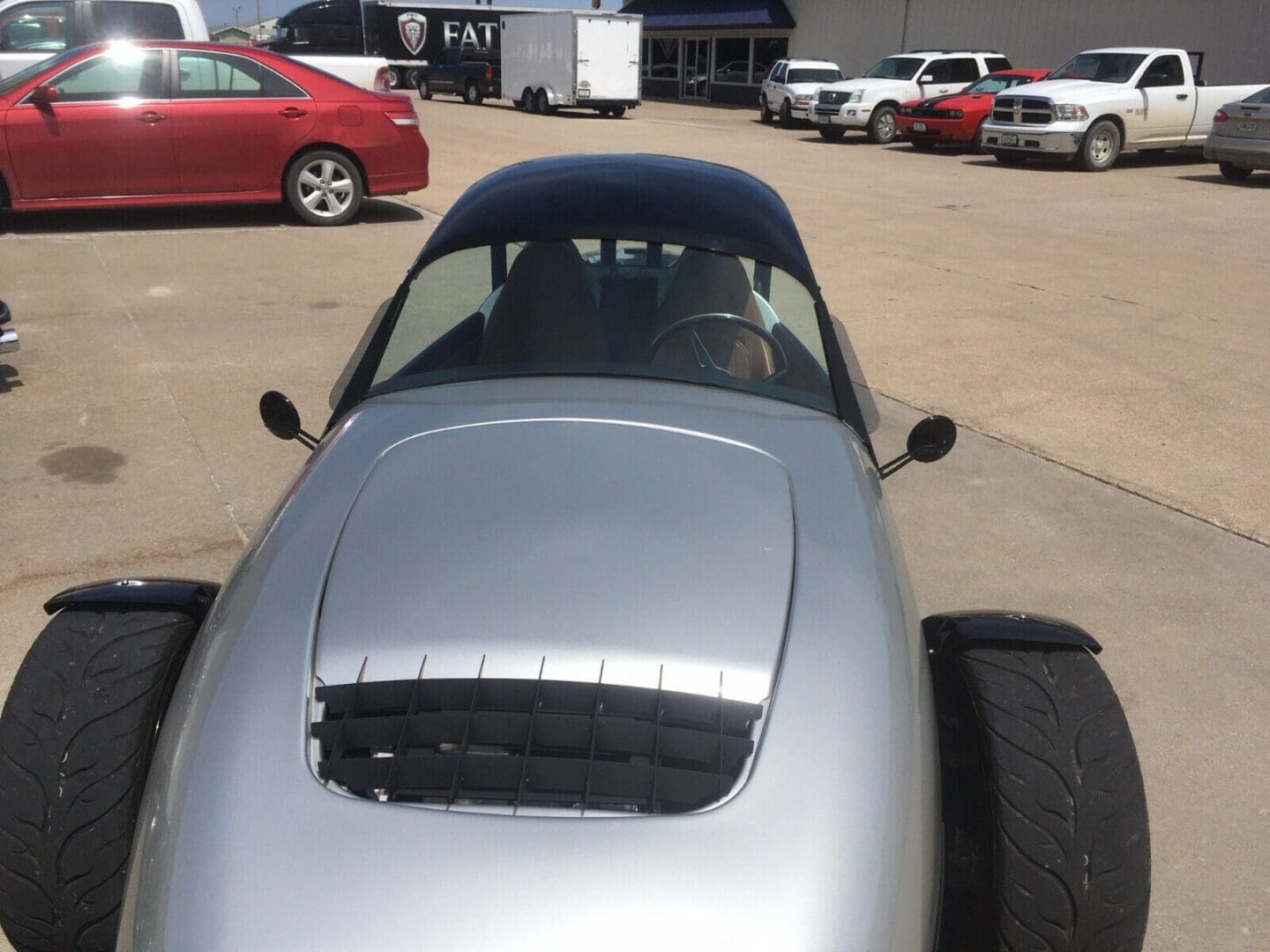 Silver sports car parked outdoors with a vented hood.