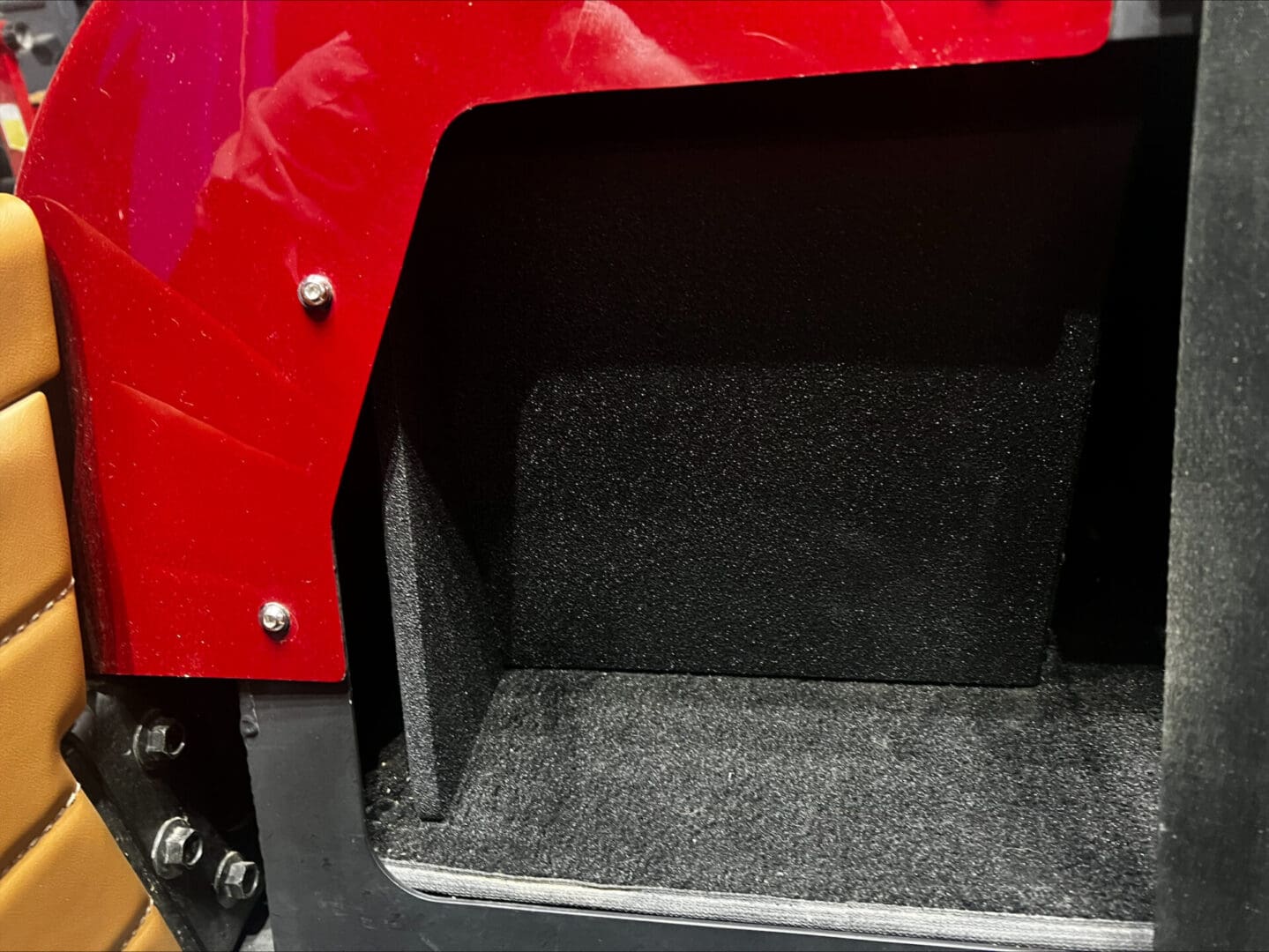Empty carpeted compartment in a vehicle with a red exterior.