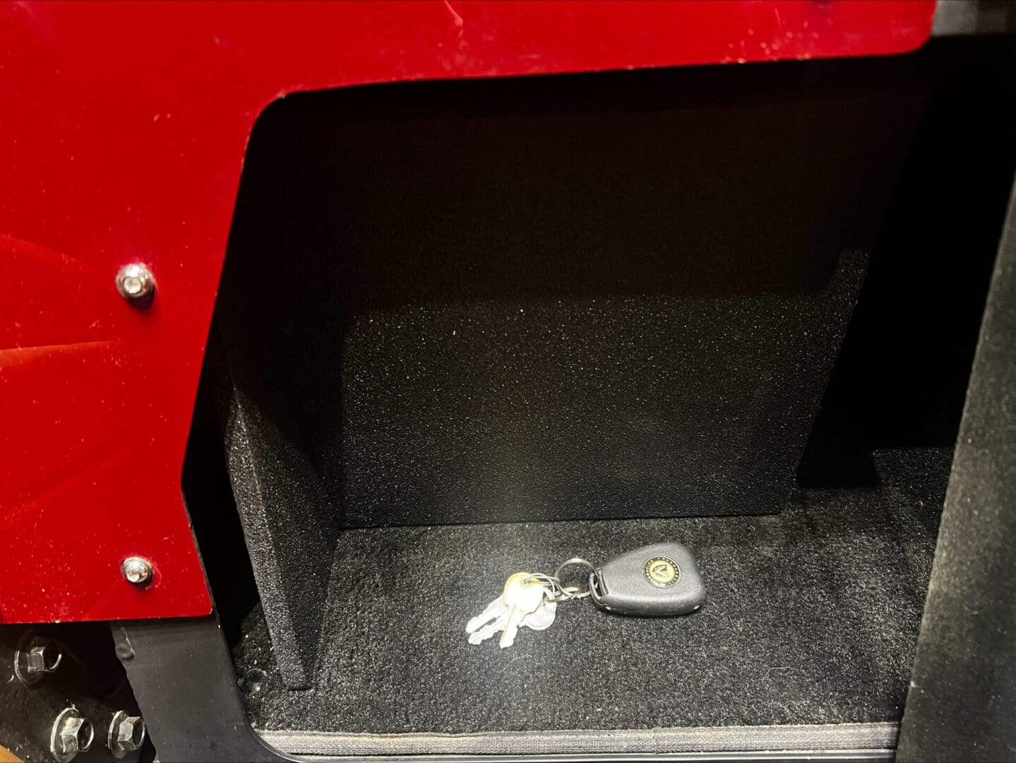 Car key and keychain resting in a vehicle's storage compartment.