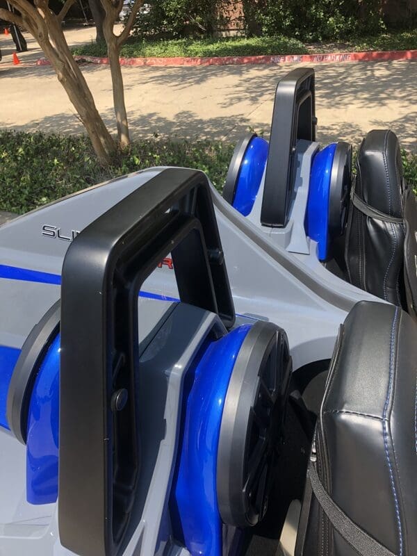 Close-up of blue and black amusement park ride seats with safety bars.