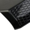 Close-up of a carbon fiber car part with hexagonal pattern.