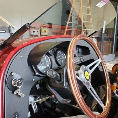 Close-up of a classic car's wooden steering wheel and dashboard.